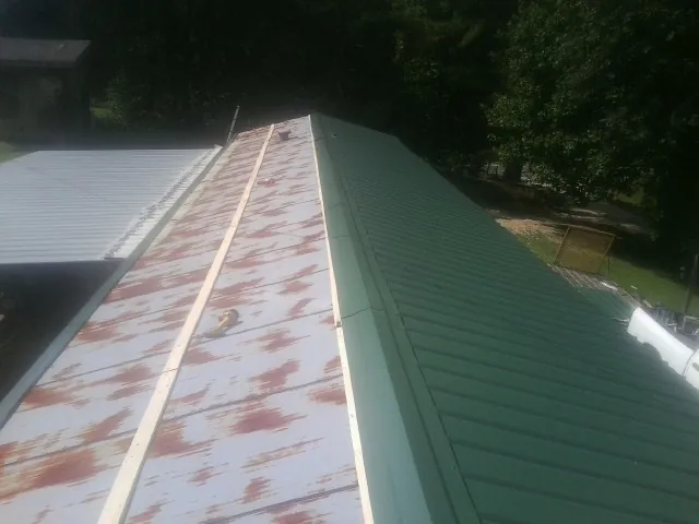 Old rusted panels beside newly installed green metal roofing — Wind Damage Roof Repair by Roofing Brothers in Eldorado Springs