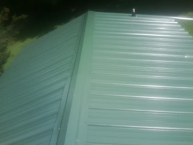 New green metal panels meeting at the ridge of a roof — Flat Roof Repair work by our crew in Eldorado Springs
