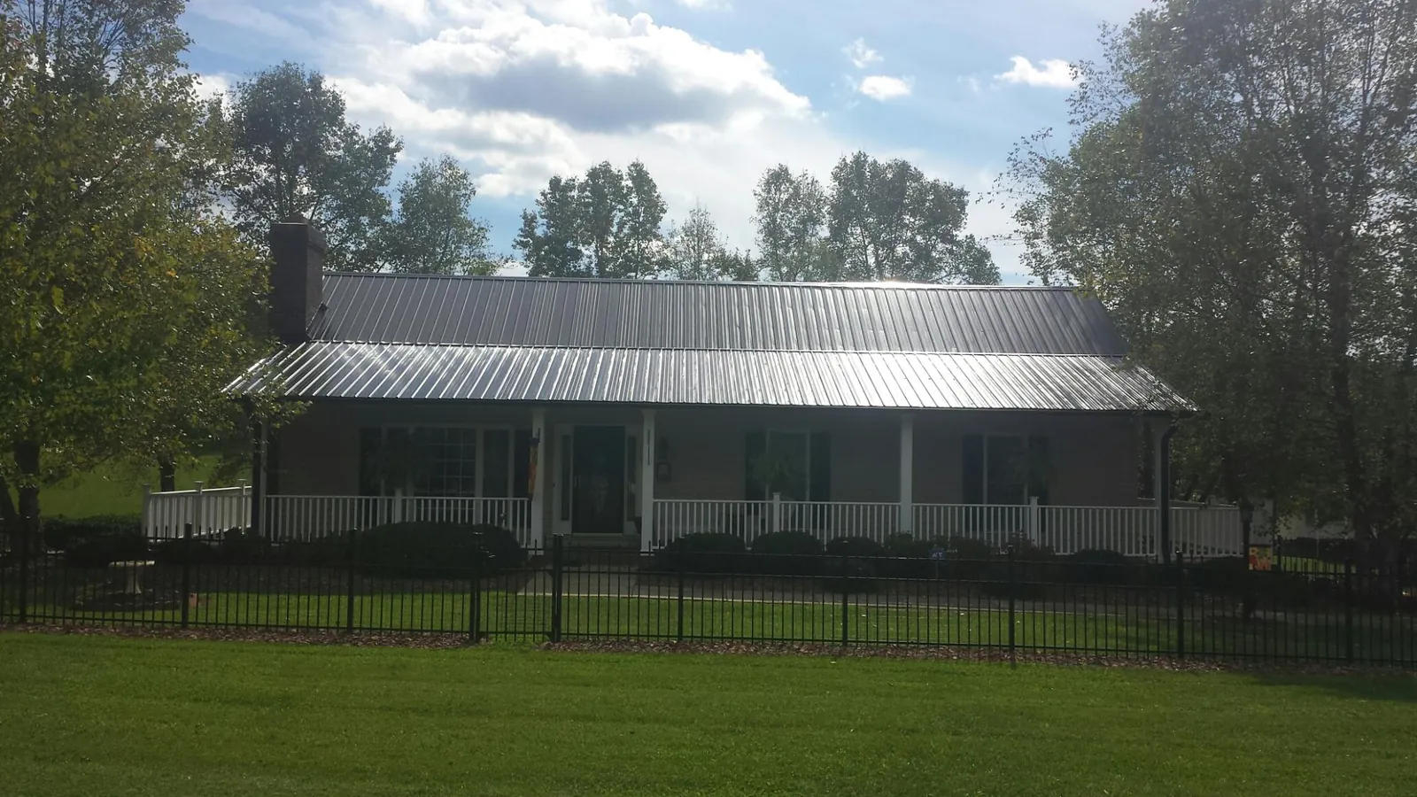 Gray metal roof on a brick ranch with a full width front porch — Gutter Guard Installation work by our crew in Eldorado Springs
