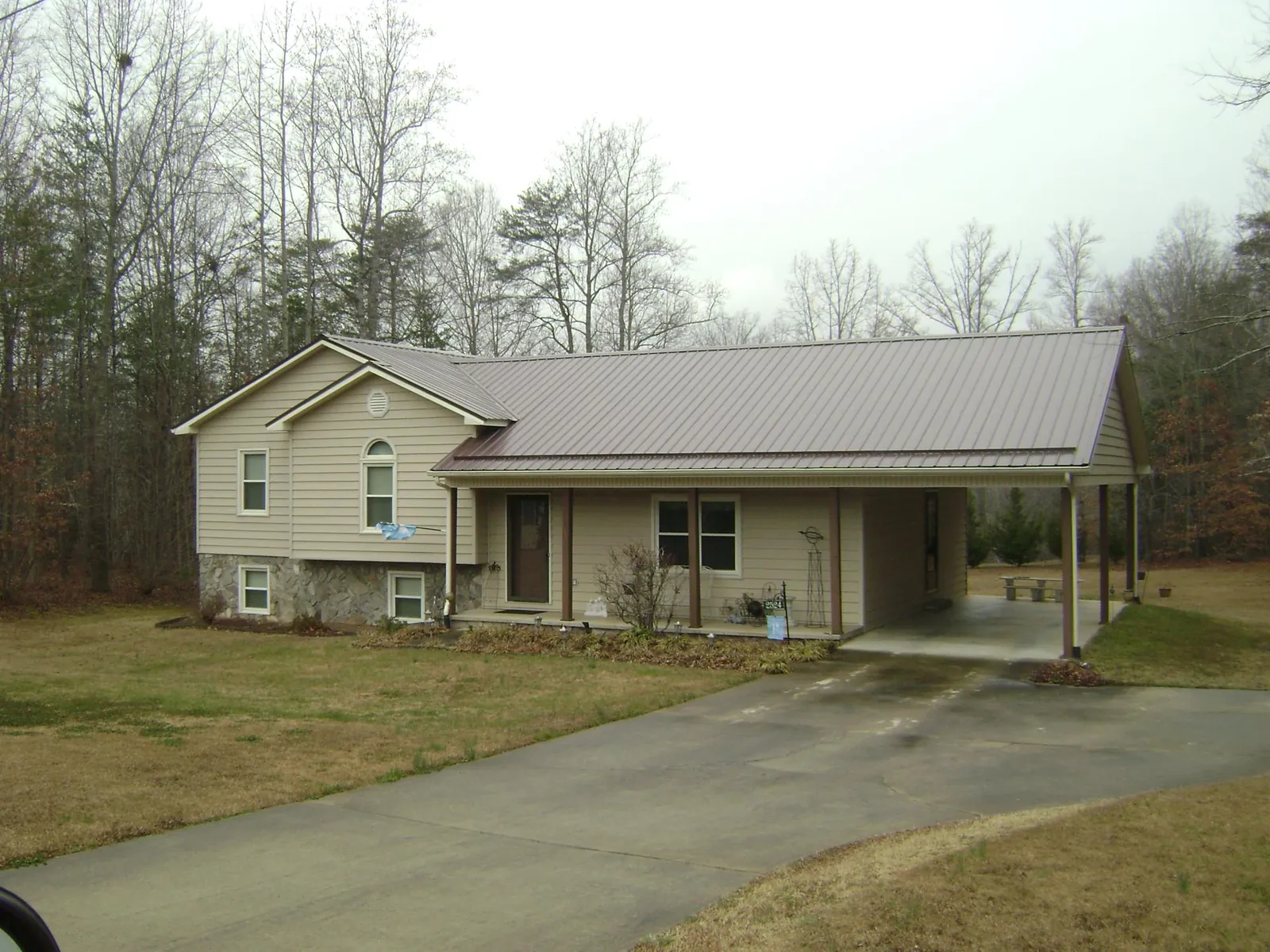 Brown metal roof on a tan split level home with an attached carport in Eldorado Springs