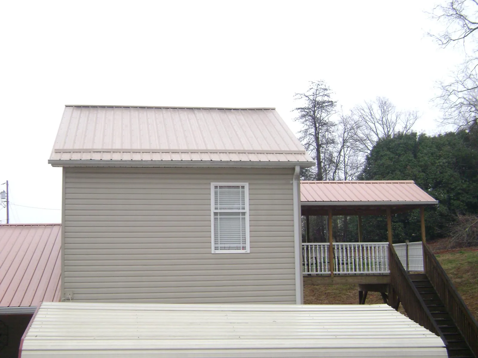 Tan metal roofs on a two story addition and attached porch, from a Roof Replacement job in Eldorado Springs