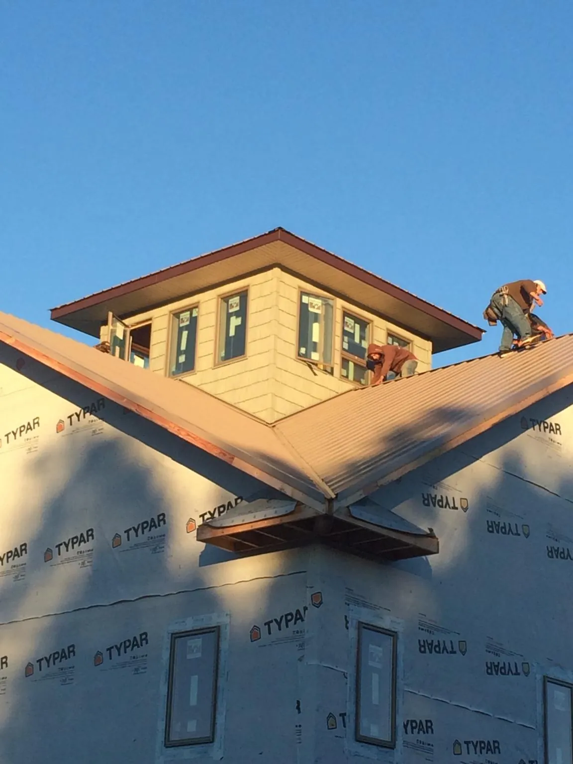 Roofers working around a rooftop cupola on a new metal roof at sunset — Roof Waterproofing in Eldorado Springs by Roofing Brothers